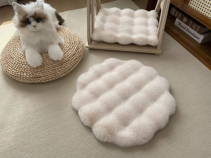 Fluffy white pet bed mat on a carpeted floor with a cat sitting on a woven pad.