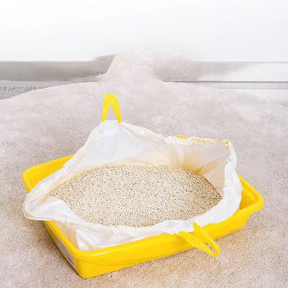 Yellow plastic litter tray with a white liner filled with litter on a light-colored surface.