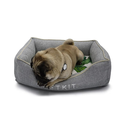 Dog lying on a grey pet bed with 'PETKIT' branding on a white background