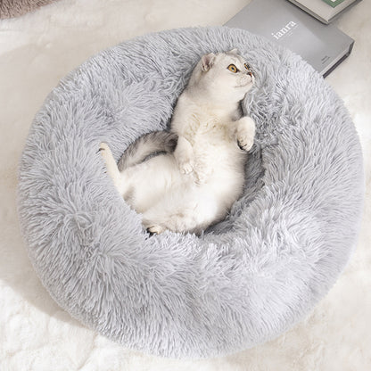 Cat lying on a fluffy gray pet bed with a carpeted background