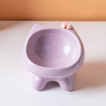 Purple cat-shaped cat bowl on a white surface with a beige background