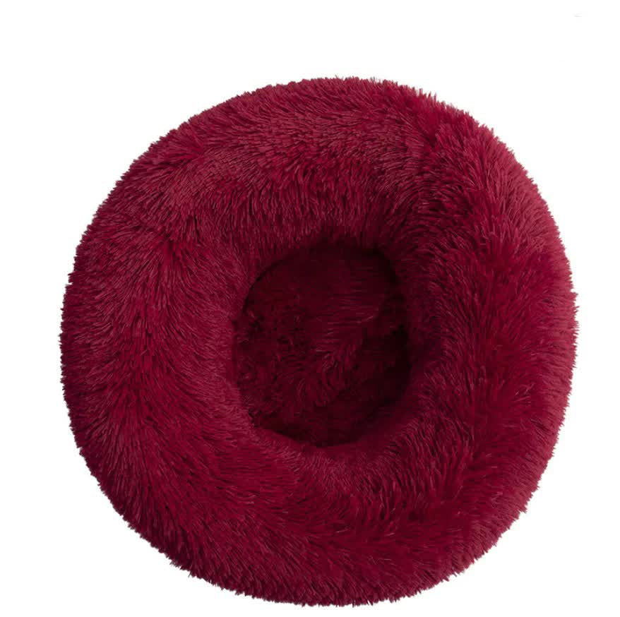 Red fluffy donut-shaped pet bed on a white background
